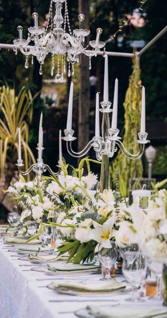 Table fleurie de blanc sous un lustre de cristal, chandeliers et bougies